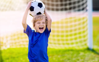 Boy with Soccer Ball in the Net